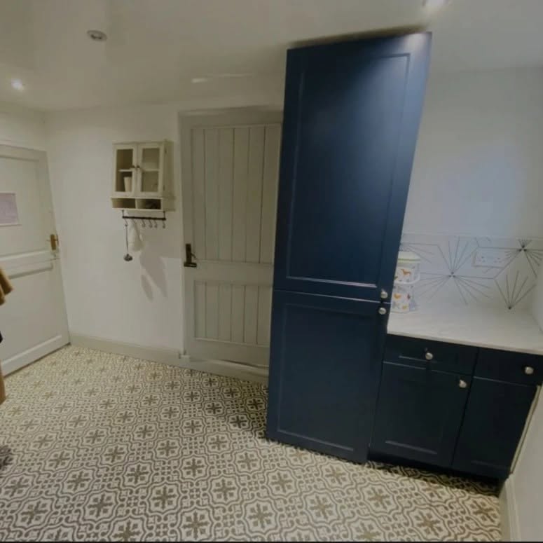 Bootroom with patterned floor tiles, navy cabinets and hexagon wall tiles