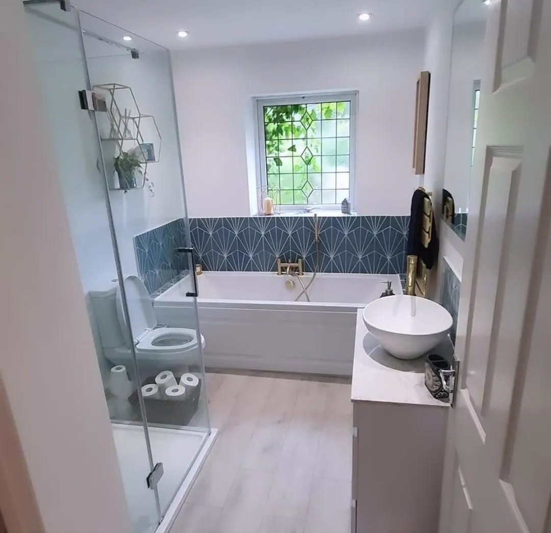Bathroom with teal fan-pattern tiles around the bath, a glass shower screen and gold fittings