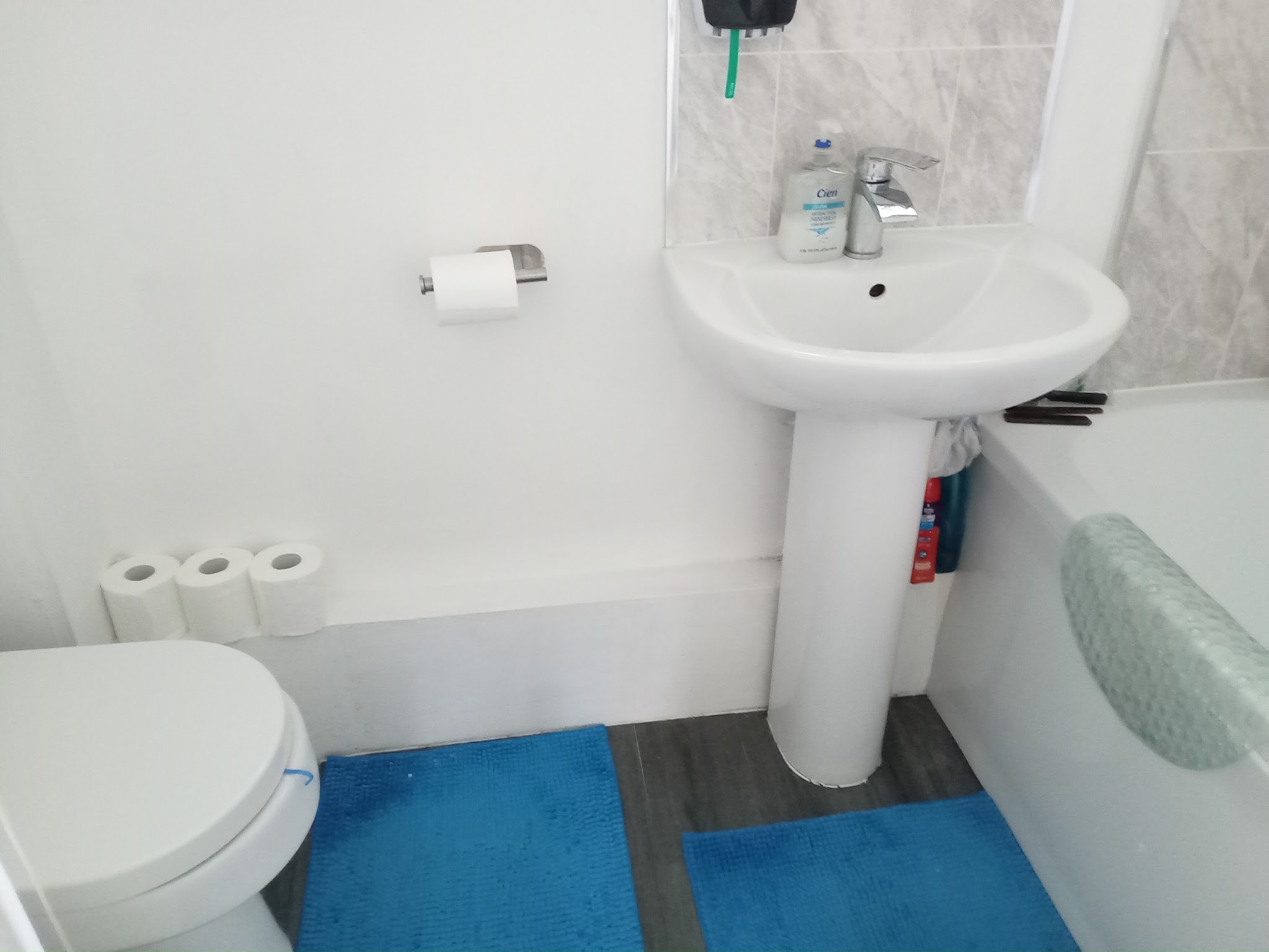White bathroom with a bath, pedestal basin and toilet, refitted with the toilet moved back