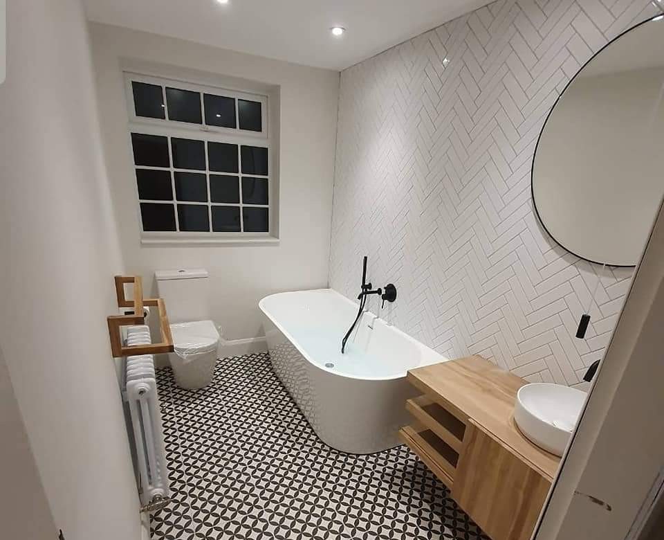 Freestanding bath with herringbone wall tiles and a black-and-white patterned floor