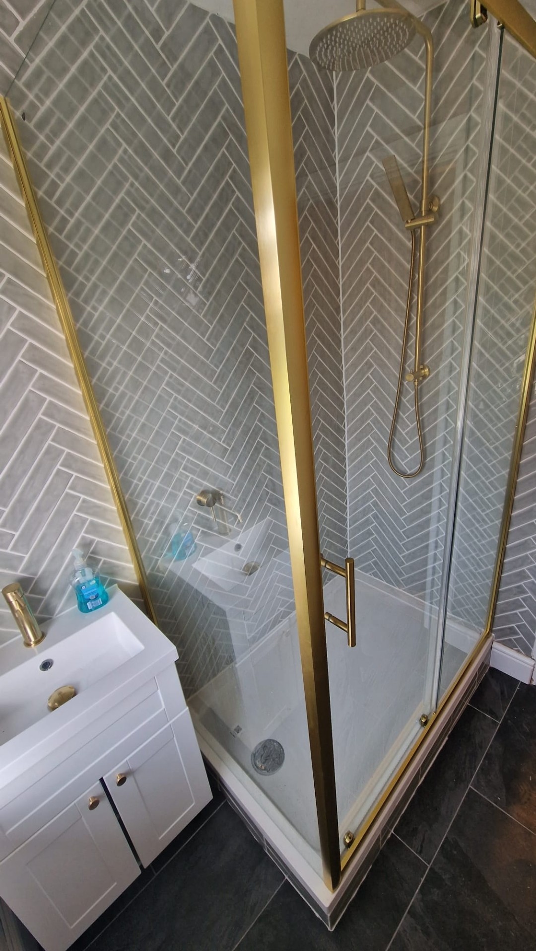 Gold-framed shower enclosure with herringbone tiles