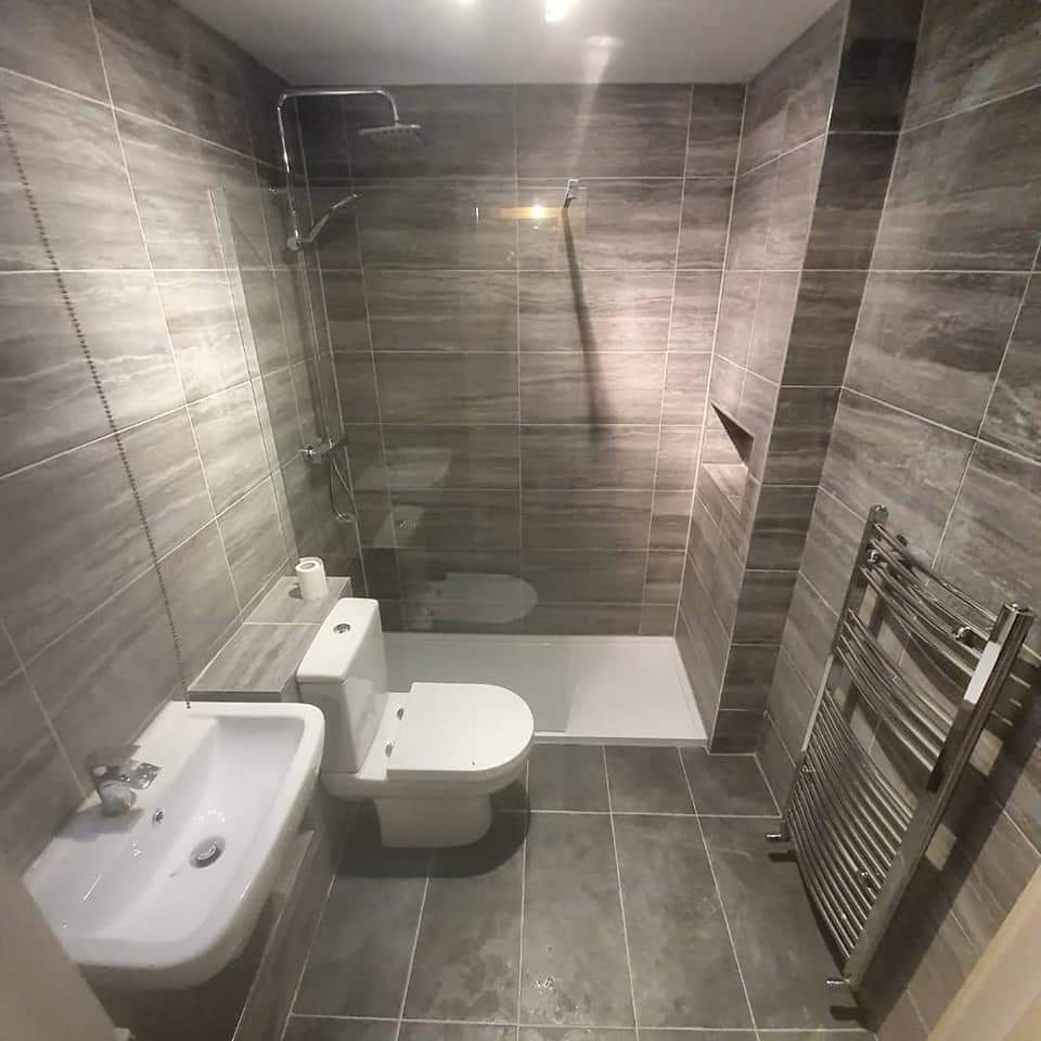 Walk-in shower with grey wood-effect tiles and a chrome towel rail